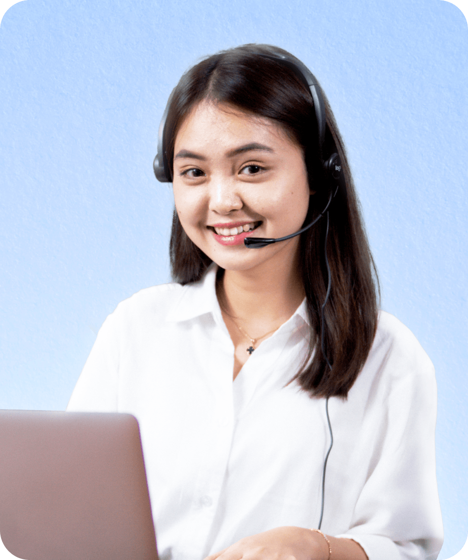 Topremit のカスタマーサポートに所属する女性が、ラップトップの前でヘッドセットを装着し笑顔を見せています。