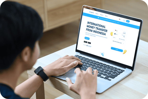Topremit のウェブサイトを画面に表示したラップトップを使用している男性。
